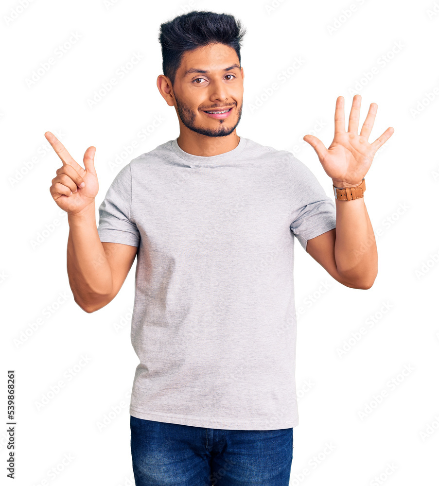 Handsome latin american young man wearing casual tshirt showing and pointing up with fingers number seven while smiling confident and happy. Handsome latin american young man wearing casual tshirt showing and pointing up with fingers number seven while smiling confident and happy.