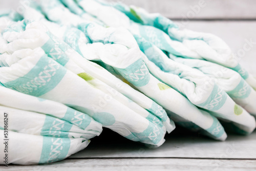 Diapers stacked vertically from left to right. Mention the amount of diapers needed to care for babies throughout their life cycle and the dedicated work of parents.