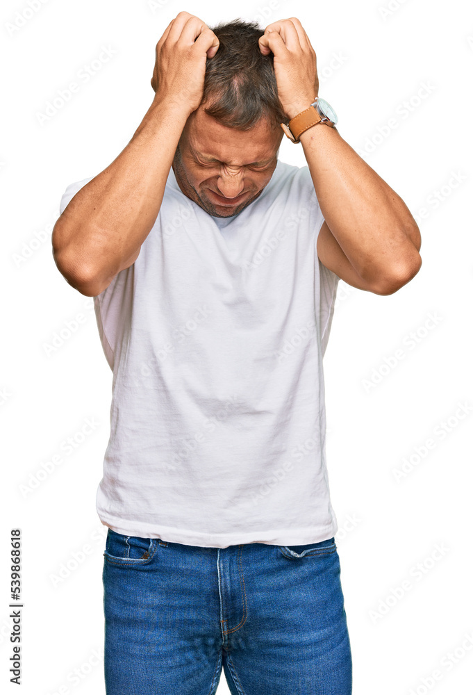 Handsome muscle man wearing casual white tshirt suffering from headache desperate and stressed because pain and migraine. hands on head. Handsome muscle man wearing casual white tshirt suffering from headache desperate and stressed because pain and migraine. hands on head.