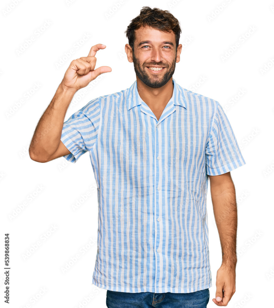 Handsome young man with beard wearing casual fresh shirt smiling and confident gesturing with hand doing small size sign with fingers looking and the camera. measure concept. Handsome young man with beard wearing casual fresh shirt smiling and confident gesturing with hand doing small size sign with fingers looking and the camera. measure concept.