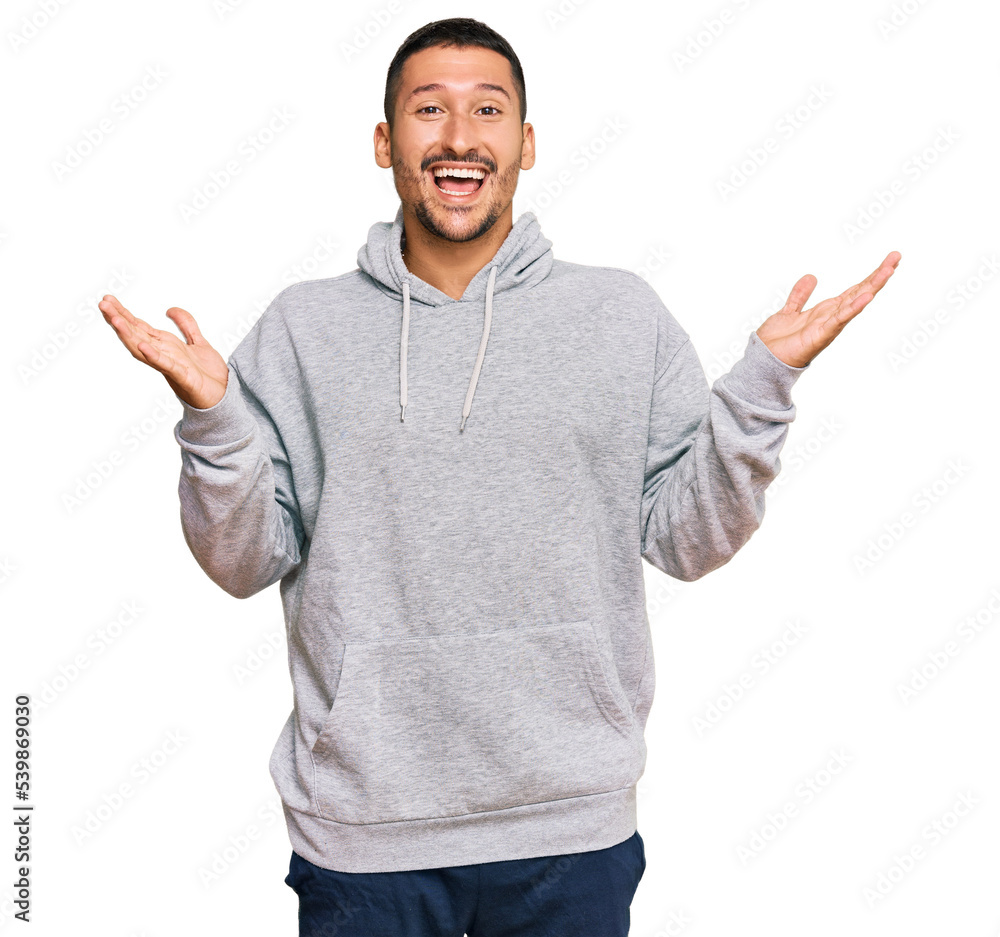 Fototapeta premium Handsome man with tattoos wearing casual sweatshirt celebrating victory with happy smile and winner expression with raised hands