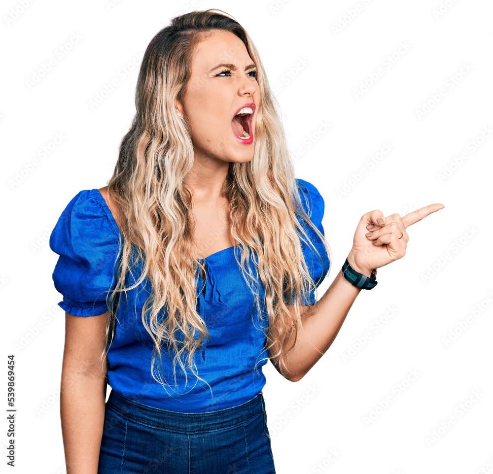 Young blonde woman pointing with fingers to the side angry and mad screaming frustrated and furious, shouting with anger. rage and aggressive concept. - obrazy, fototapety, plakaty 