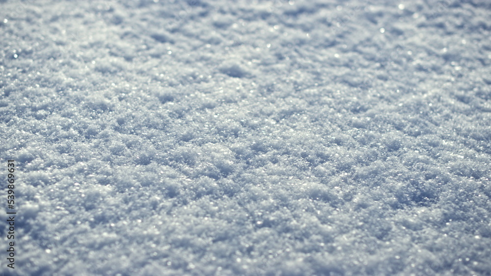 Sparkling white snow crystals covering ground wintertime close up. Snow shining.