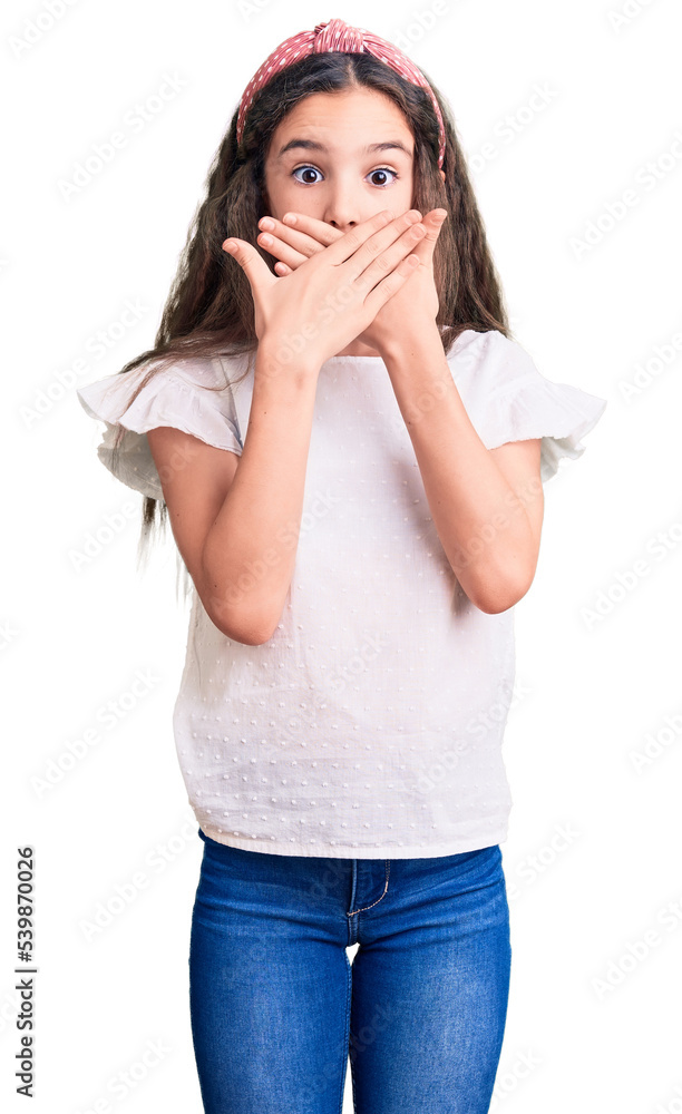 Cute hispanic child girl wearing casual white tshirt shocked covering mouth with hands for mistake. secret concept. Cute hispanic child girl wearing casual white tshirt shocked covering mouth with hands for mistake. secret concept.