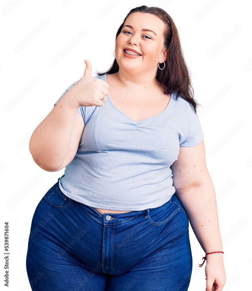 Fototapeta premium Young plus size woman wearing casual clothes doing happy thumbs up gesture with hand. approving expression looking at the camera showing success.