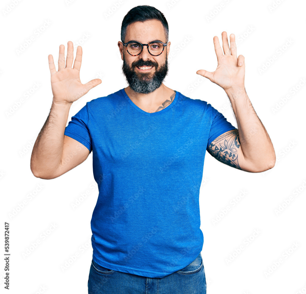 Fototapeta premium Hispanic man with beard wearing casual t shirt and glasses showing and pointing up with fingers number nine while smiling confident and happy.