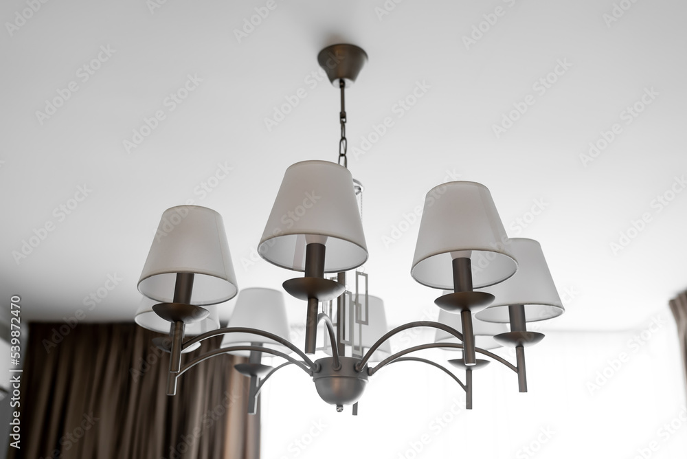 A round chandelier of several lamps against a light ceiling, full frame, side view A round chandelier of several lamps against a light ceiling, full frame, side view