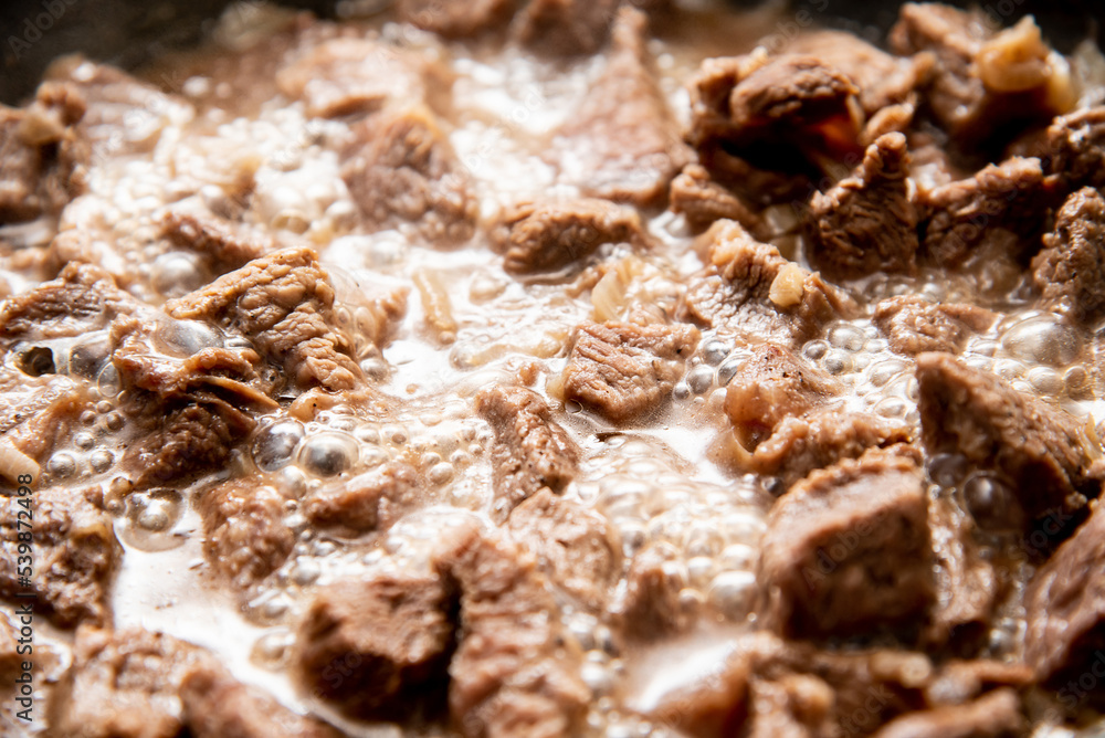 close-up beautiful large pieces of fried meat with onions in a pan close-up beautiful large pieces of fried meat with onions in a pan