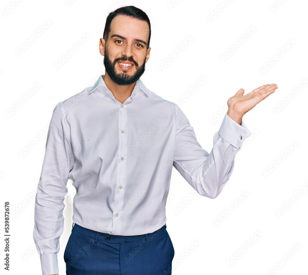 Young man with beard wearing business shirt smiling cheerful presenting and pointing with palm of hand looking at the camera. Young man with beard wearing business shirt smiling cheerful presenting and pointing with palm of hand looking at the camera.