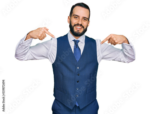 Young man with beard wearing business vest looking confident with smile on face, pointing oneself with fingers proud and happy.