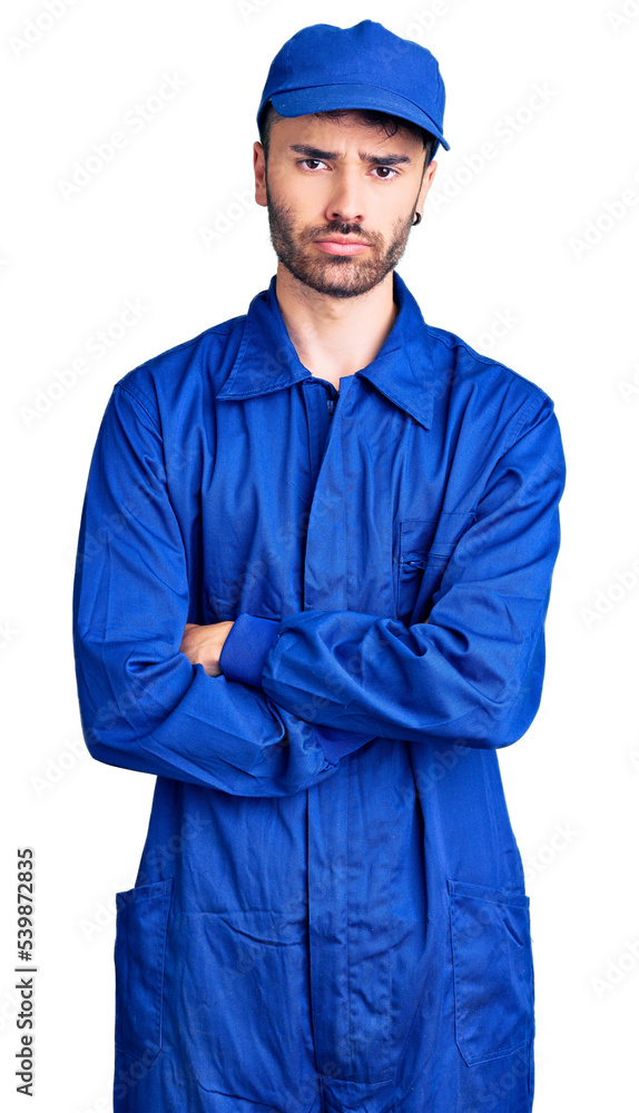 Young hispanic man wearing painter uniform skeptic and nervous, disapproving expression on face with crossed arms. negative person. Young hispanic man wearing painter uniform skeptic and nervous, disapproving expression on face with crossed arms. negative person.
