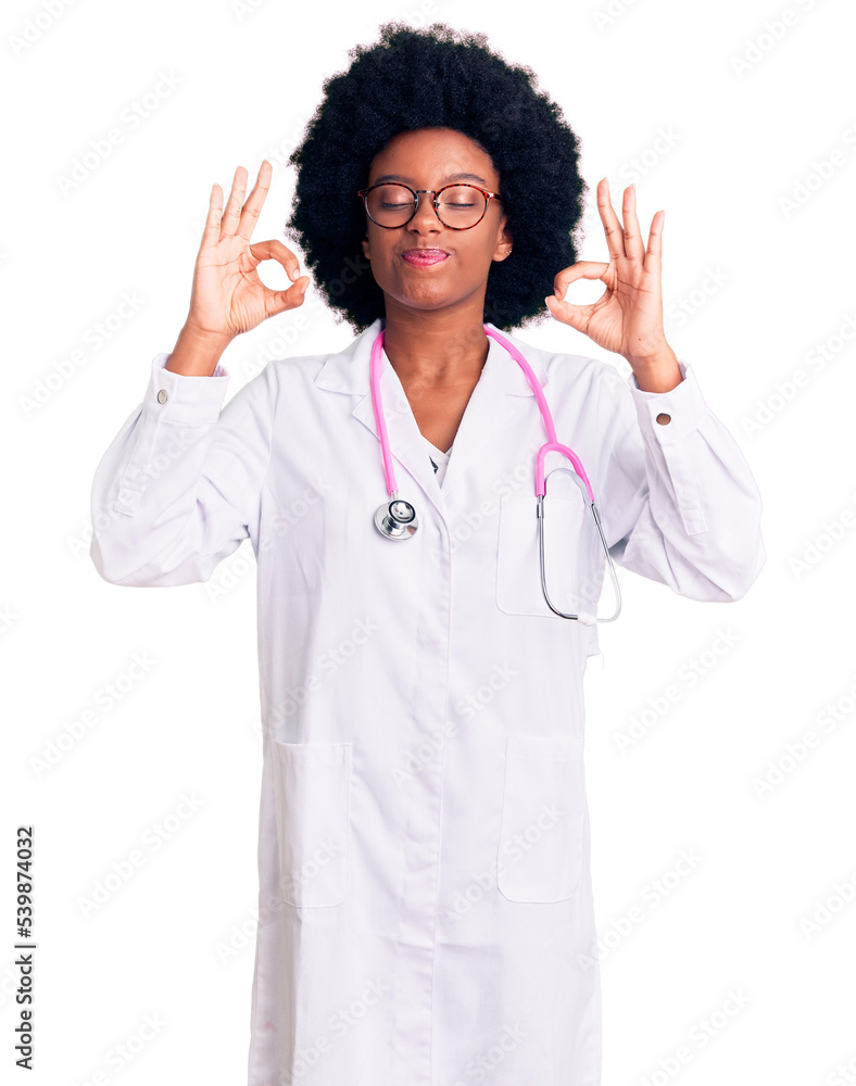 Young african american woman wearing doctor coat and stethoscope relaxed and smiling with eyes closed doing meditation gesture with fingers. yoga concept.
