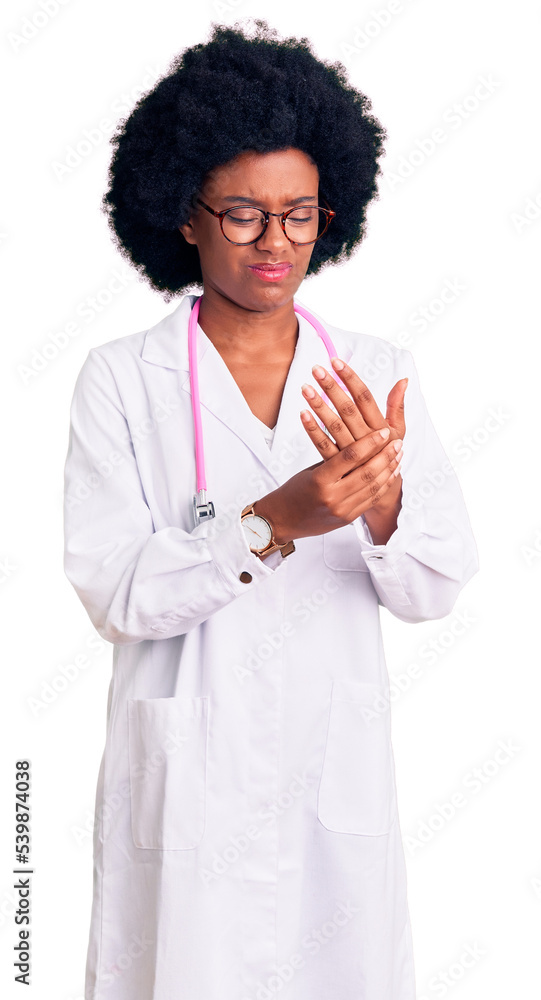 Young african american woman wearing doctor coat and stethoscope suffering pain on hands and fingers, arthritis inflammation Young african american woman wearing doctor coat and stethoscope suffering pain on hands and fingers, arthritis inflammation