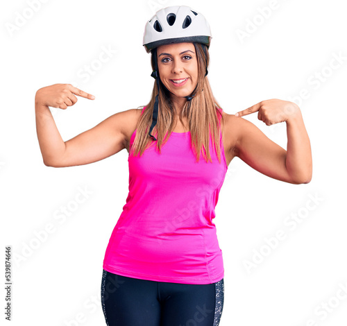 Young beautiful woman wearing bike helmet looking confident with smile on face, pointing oneself with fingers proud and happy. © Krakenimages.com
