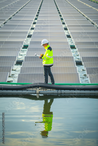 Portrait of professional man engineer working checking the panels at solar energy on buoy floating. Power plant with water, renewable energy source. Eco technology for electric power in industry.