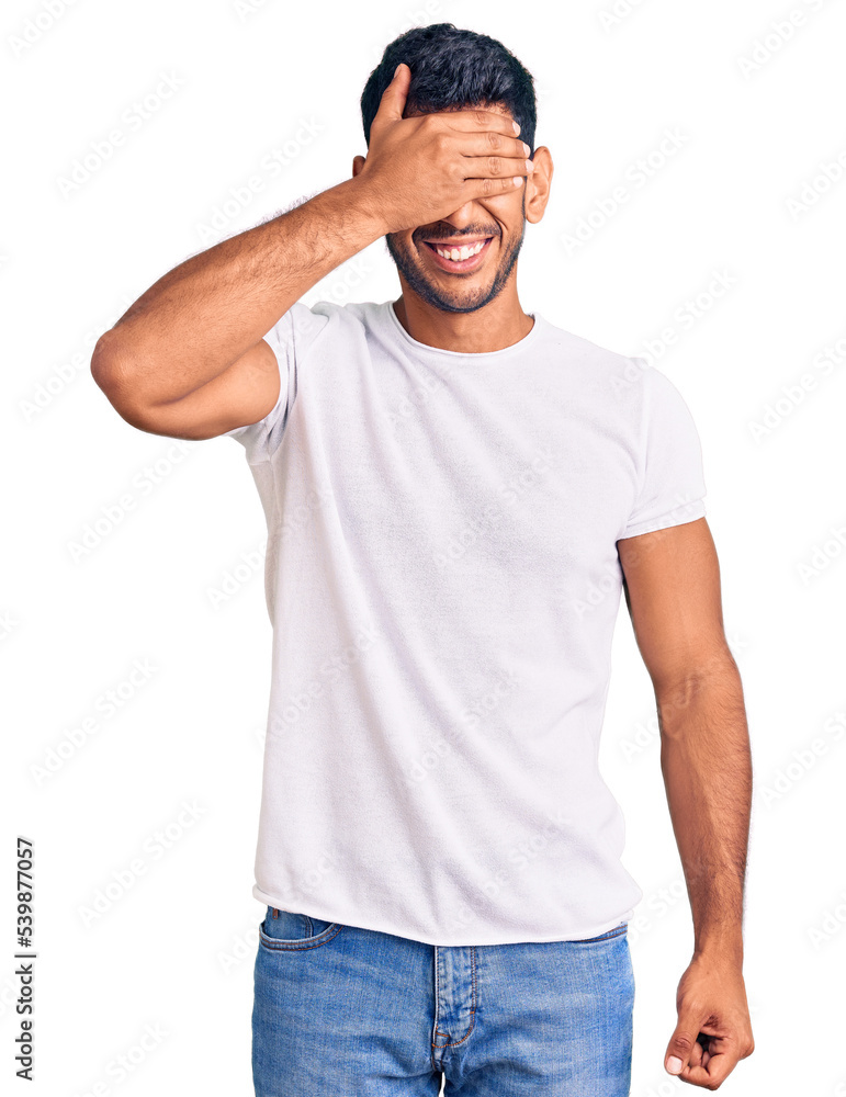 Young latin man wearing casual clothes smiling and laughing with hand on face covering eyes for surprise. blind concept. Young latin man wearing casual clothes smiling and laughing with hand on face covering eyes for surprise. blind concept.