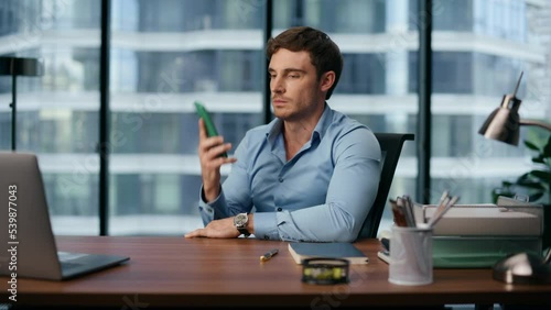 Stressed boss talking mobile office interior. Nervous man picking up cellphone