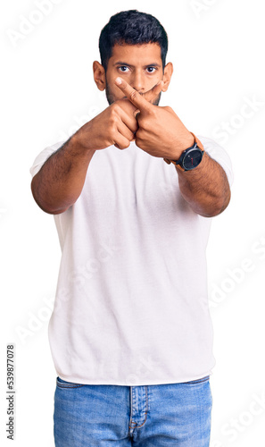 Young latin man wearing casual clothes rejection expression crossing fingers doing negative sign