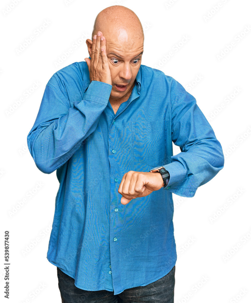 Middle age bald man wearing casual clothes looking at the watch time worried, afraid of getting late Middle age bald man wearing casual clothes looking at the watch time worried, afraid of getting late