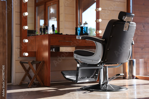 Stylish hairdresser's workplace with professional armchair and beautiful big mirror in barbershop