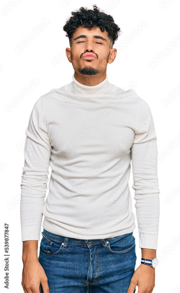 Young arab man wearing casual winter sweater looking at the camera blowing a kiss on air being lovely and sexy. love expression. Young arab man wearing casual winter sweater looking at the camera blowing a kiss on air being lovely and sexy. love expression.