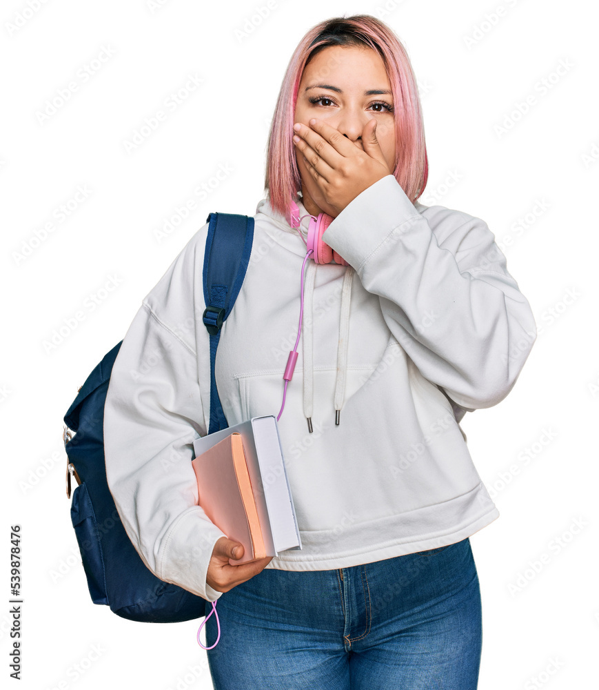 Hispanic woman with pink hair wearing student backpack and headphones shocked covering mouth with hands for mistake. secret concept. Hispanic woman with pink hair wearing student backpack and headphones shocked covering mouth with hands for mistake. secret concept.