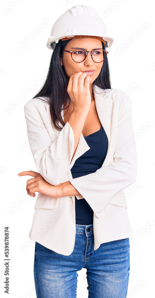 Young beautiful latin girl wearing architect hardhat and glasses looking stressed and nervous with hands on mouth biting nails. anxiety problem. Young beautiful latin girl wearing architect hardhat and glasses looking stressed and nervous with hands on mouth biting nails. anxiety problem.