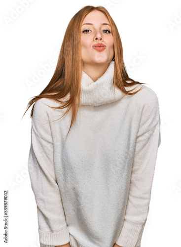 Young irish woman wearing casual winter sweater looking at the camera blowing a kiss on air being lovely and sexy. love expression. © Krakenimages.com