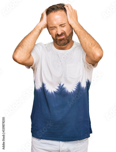 Handsome middle age man wearing casual tie dye tshirt suffering from headache desperate and stressed because pain and migraine. hands on head.