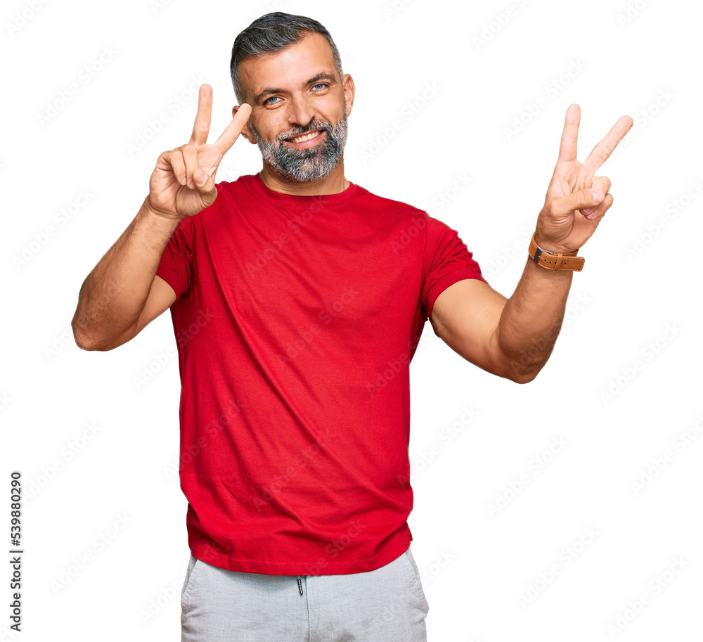 Middle age handsome man wearing casual clothes smiling looking to the camera showing fingers doing victory sign. number two.