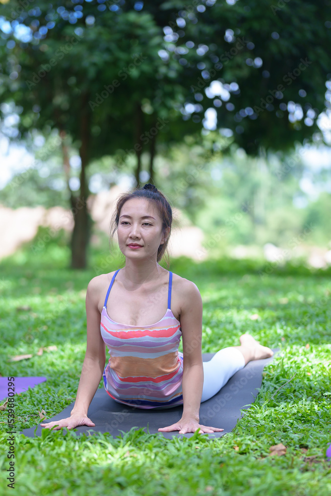 A beautiful young woman group of adults attending a yoga class outside the park., peace and relaxation, woman's happiness