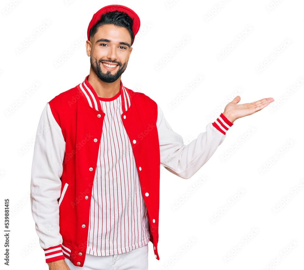 Young man with beard wearing baseball uniform smiling cheerful presenting and pointing with palm of hand looking at the camera. Young man with beard wearing baseball uniform smiling cheerful presenting and pointing with palm of hand looking at the camera.