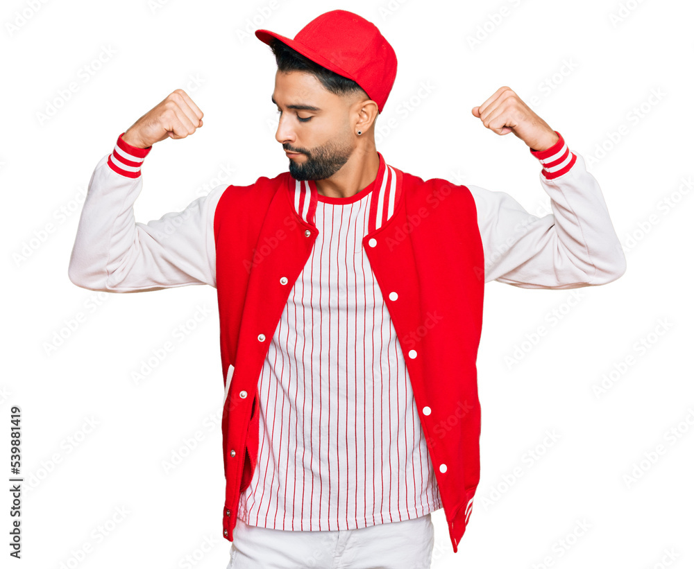 Young man with beard wearing baseball uniform showing arms muscles smiling proud. fitness concept. Young man with beard wearing baseball uniform showing arms muscles smiling proud. fitness concept.