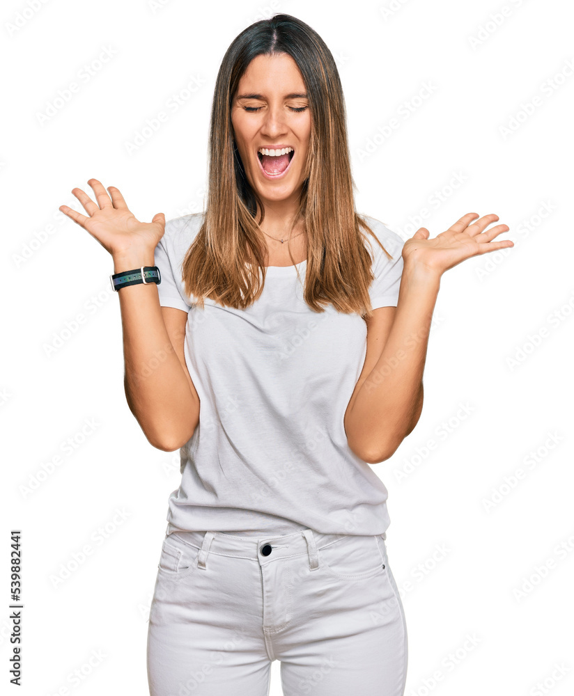 Young woman wearing casual white t shirt celebrating mad and crazy for success with arms raised and closed eyes screaming excited. winner concept Young woman wearing casual white t shirt celebrating mad and crazy for success with arms raised and closed eyes screaming excited. winner concept