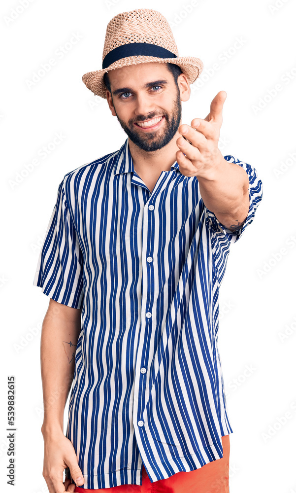 Young handsome man with beard wearing summer hat and striped shirt smiling friendly offering handshake as greeting and welcoming. successful business. Young handsome man with beard wearing summer hat and striped shirt smiling friendly offering handshake as greeting and welcoming. successful business.