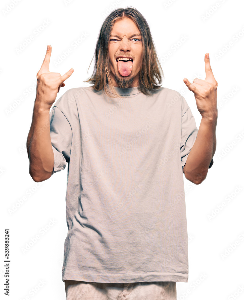 Handsome caucasian man with long hair wearing casual clothes shouting with crazy expression doing rock symbol with hands up. music star. heavy concept. Handsome caucasian man with long hair wearing casual clothes shouting with crazy expression doing rock symbol with hands up. music star. heavy concept.