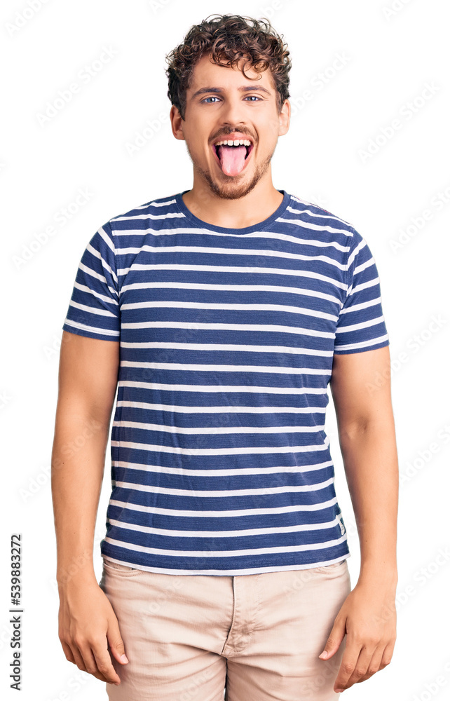Young handsome man with curly hair wearing casual clothes sticking tongue out happy with funny expression. emotion concept. Young handsome man with curly hair wearing casual clothes sticking tongue out happy with funny expression. emotion concept.
