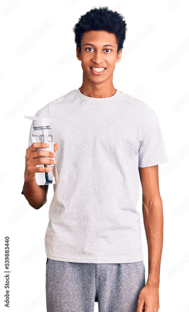 Young african american man wearing sportswear holding water bottle looking positive and happy standing and smiling with a confident smile showing teeth Young african american man wearing sportswear holding water bottle looking positive and happy standing and smiling with a confident smile showing teeth