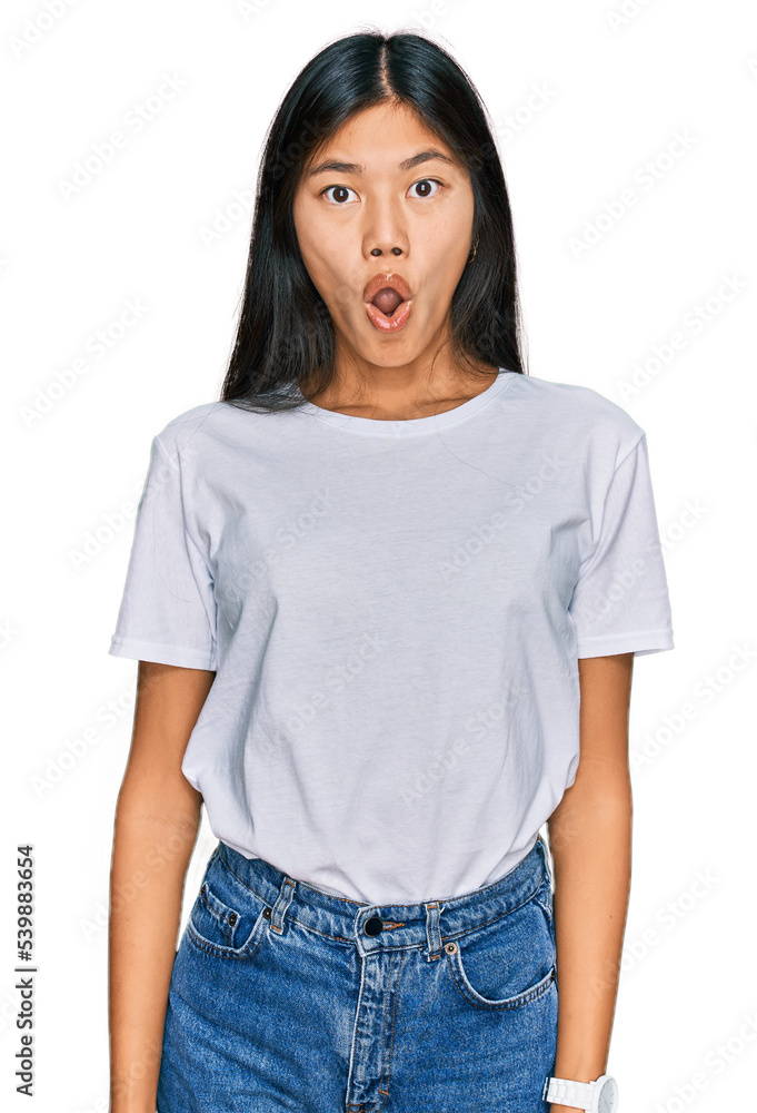 Beautiful young asian woman wearing casual white t shirt in shock face, looking skeptical and sarcastic, surprised with open mouth Beautiful young asian woman wearing casual white t shirt in shock face, looking skeptical and sarcastic, surprised with open mouth