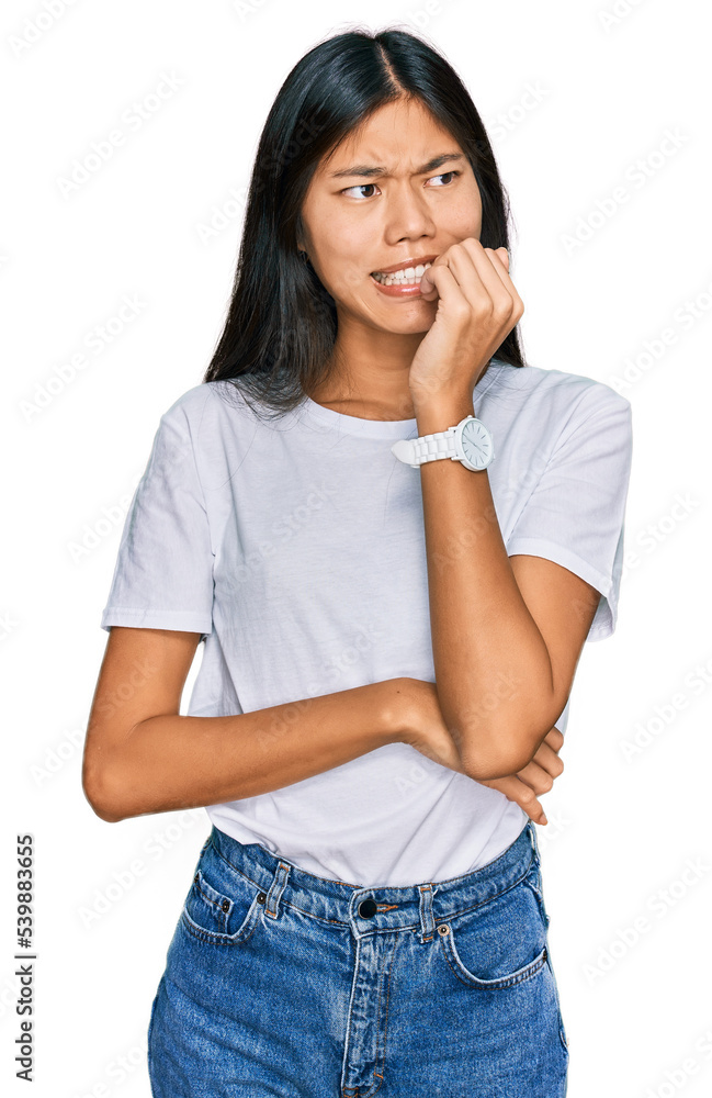 Beautiful young asian woman wearing casual white t shirt looking stressed and nervous with hands on mouth biting nails. anxiety problem. Beautiful young asian woman wearing casual white t shirt looking stressed and nervous with hands on mouth biting nails. anxiety problem.