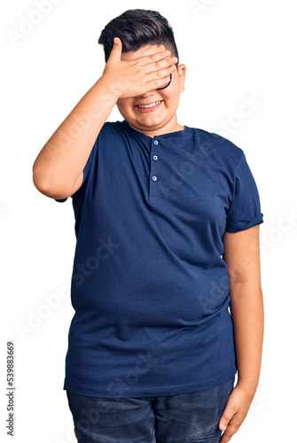 Little boy kid wearing casual clothes and glasses smiling and laughing with hand on face covering eyes for surprise. blind concept.