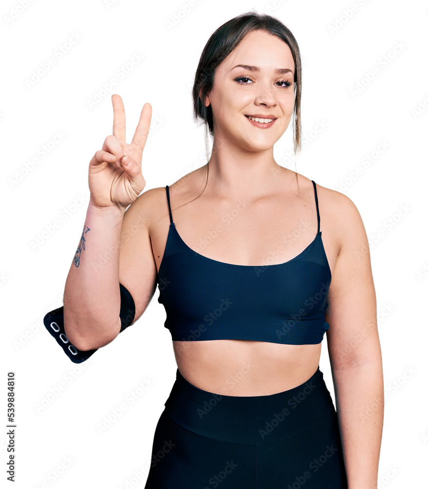 Young hispanic woman wearing sportswear showing and pointing up with fingers number two while smiling confident and happy. Young hispanic woman wearing sportswear showing and pointing up with fingers number two while smiling confident and happy.