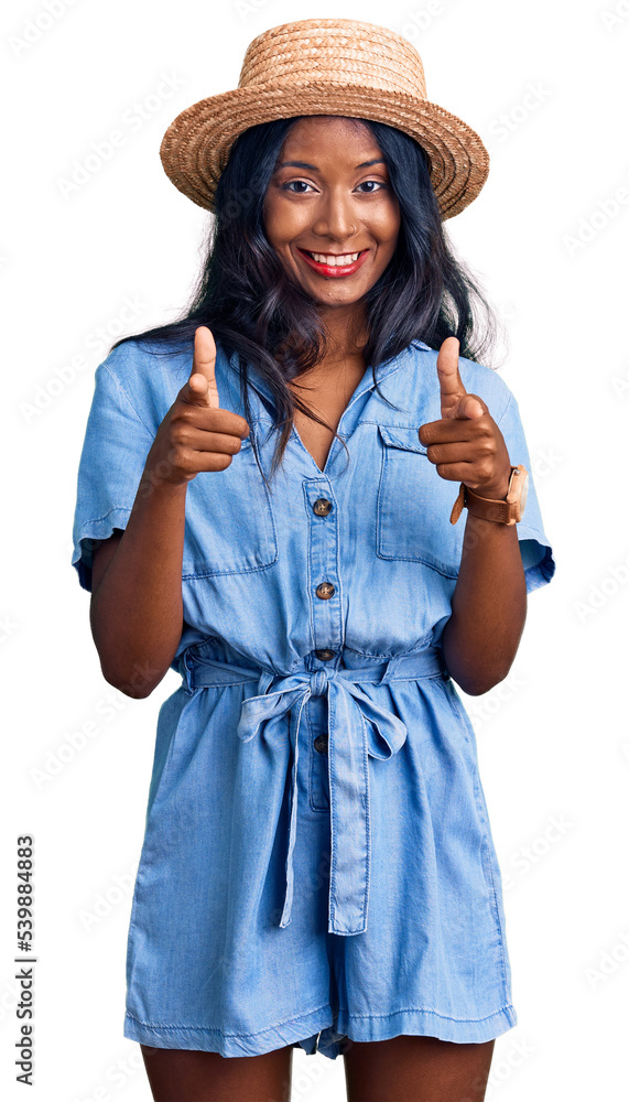 Young indian girl wearing summer hat pointing fingers to camera with happy and funny face. good energy and vibes. Young indian girl wearing summer hat pointing fingers to camera with happy and funny face. good energy and vibes.
