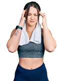 Young hispanic girl wearing sportswear and towel with hand on head, headache because stress. suffering migraine.