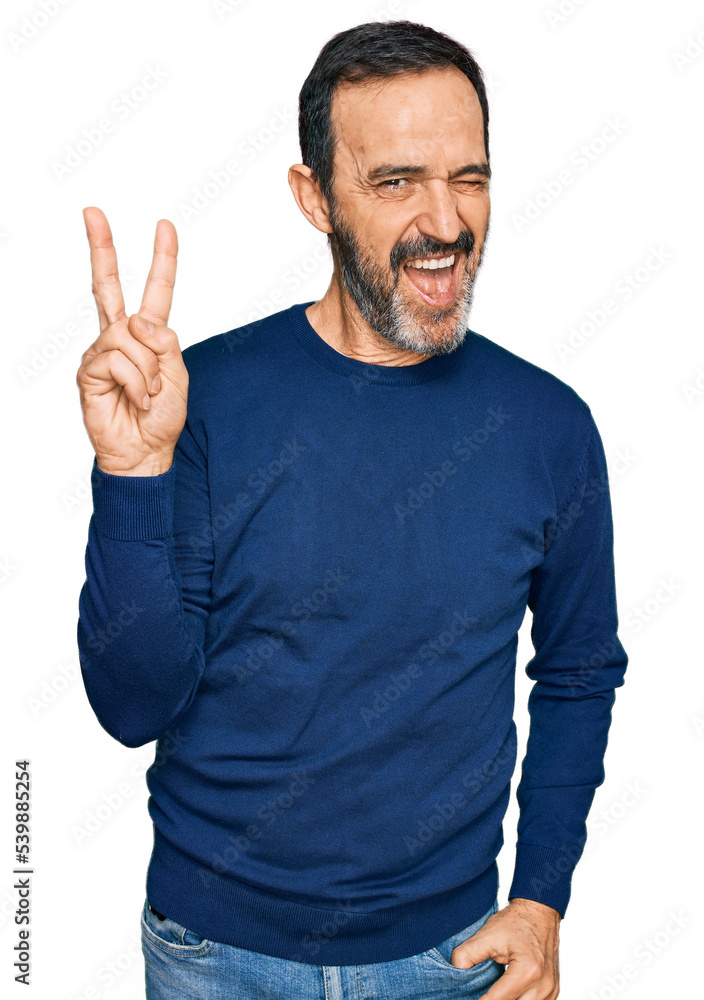 Middle age hispanic man wearing casual clothes smiling with happy face winking at the camera doing victory sign. number two. Middle age hispanic man wearing casual clothes smiling with happy face winking at the camera doing victory sign. number two.