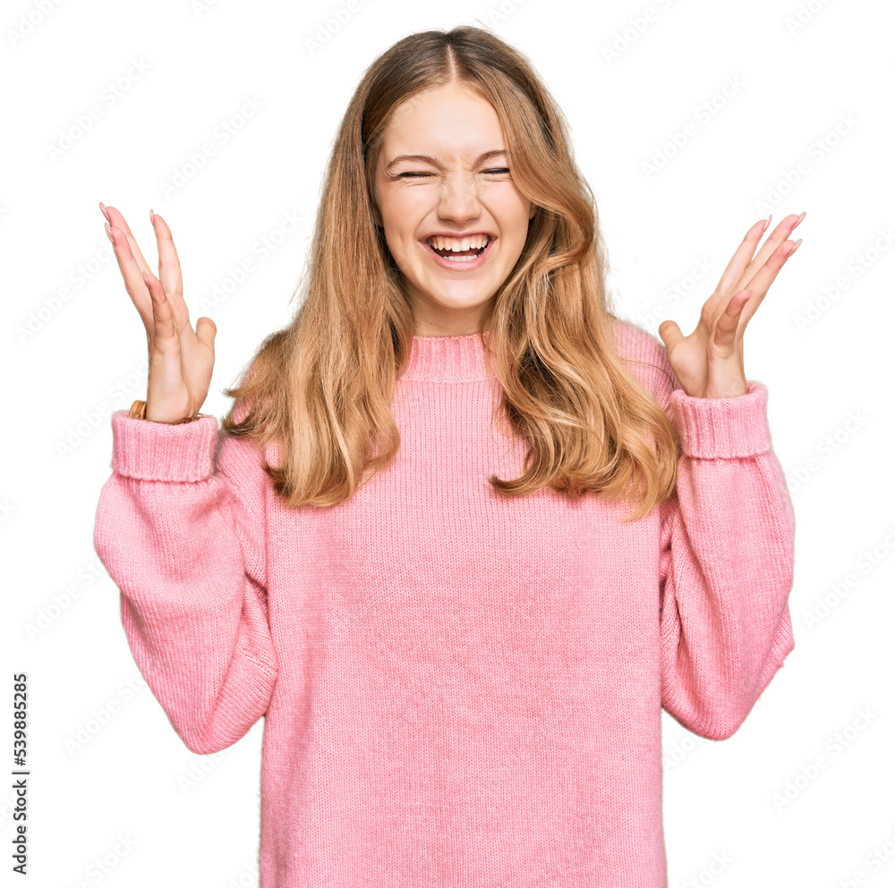 Beautiful young caucasian girl wearing casual winter sweater celebrating mad and crazy for success with arms raised and closed eyes screaming excited. winner concept Beautiful young caucasian girl wearing casual winter sweater celebrating mad and crazy for success with arms raised and closed eyes screaming excited. winner concept