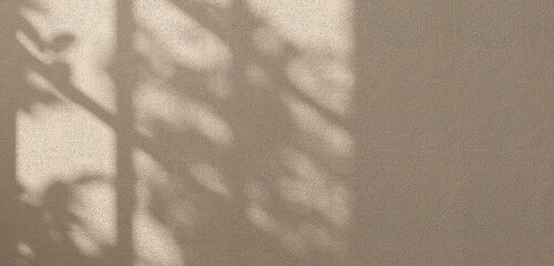 Sunlight from window cast beautiful foliage tropical leaf shadow pattern on empty brown concrete wall for tropical nature, sustainability, environmental friendly concept product display background