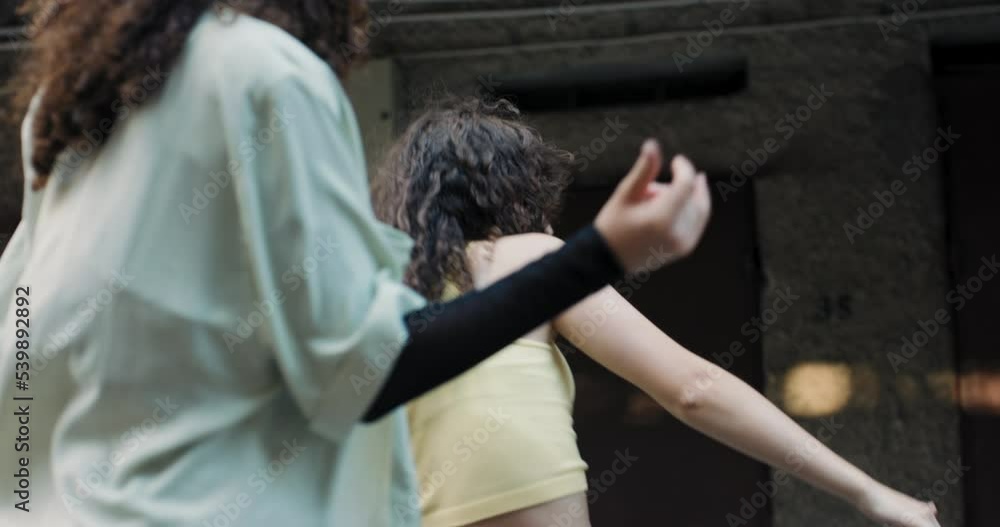 Two twin girls dance a choreographed dance together. They are training, preparing for a street dance championship, a school competition.