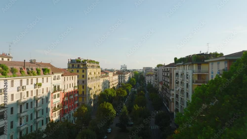 Fly above wide green boulevard between multistorey residential buildings in urban borough. Aerial morning shot. Milano, Italy Fly above wide green boulevard between multistorey residential buildings in urban borough. Aerial morning shot. Milano, Italy