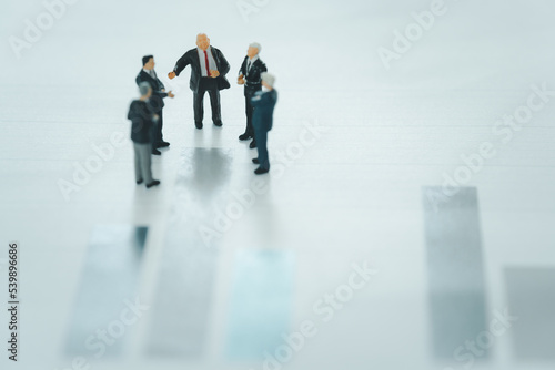 Selective focus of miniature businessman meeting and discuss on a graph financial, background as partnership and investment concept. Financial, business concept.